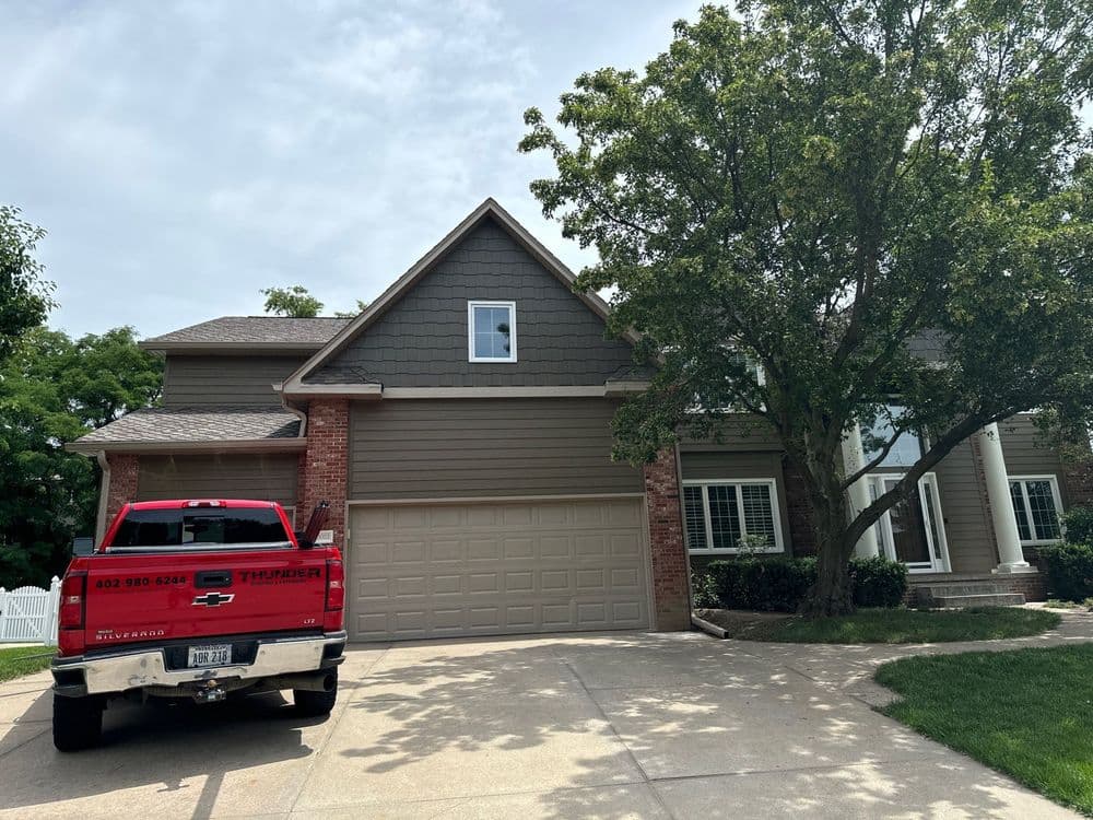 Red truck parked in front of a two-story house with a spacious driveway and green landscaping.